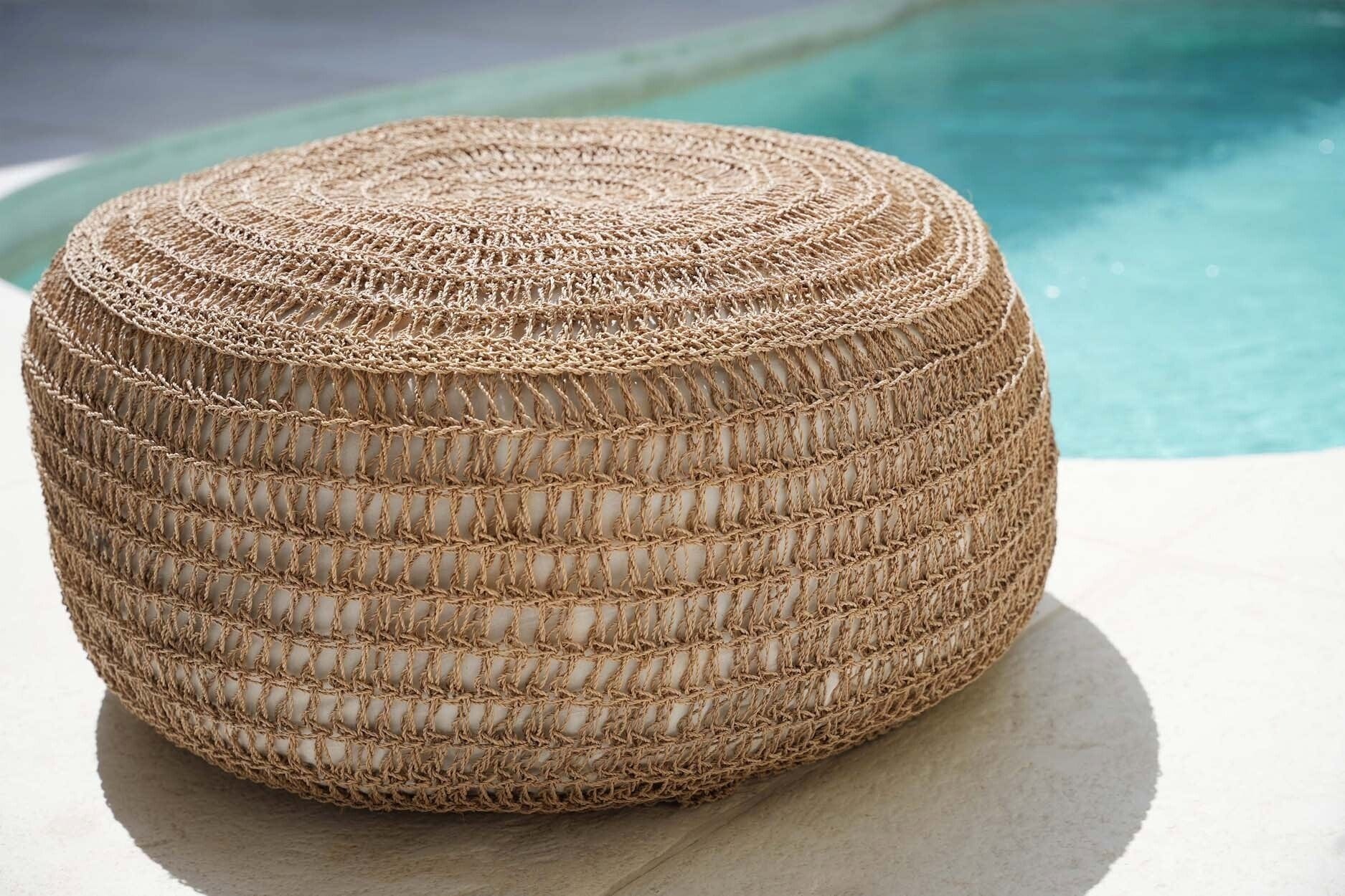 Woven ottoman on a poolside surface