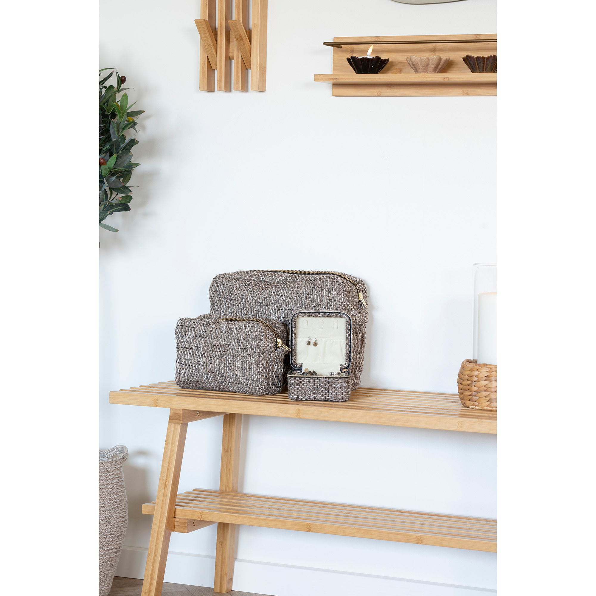 Set of woven baskets on a wooden shelf against a white wall.