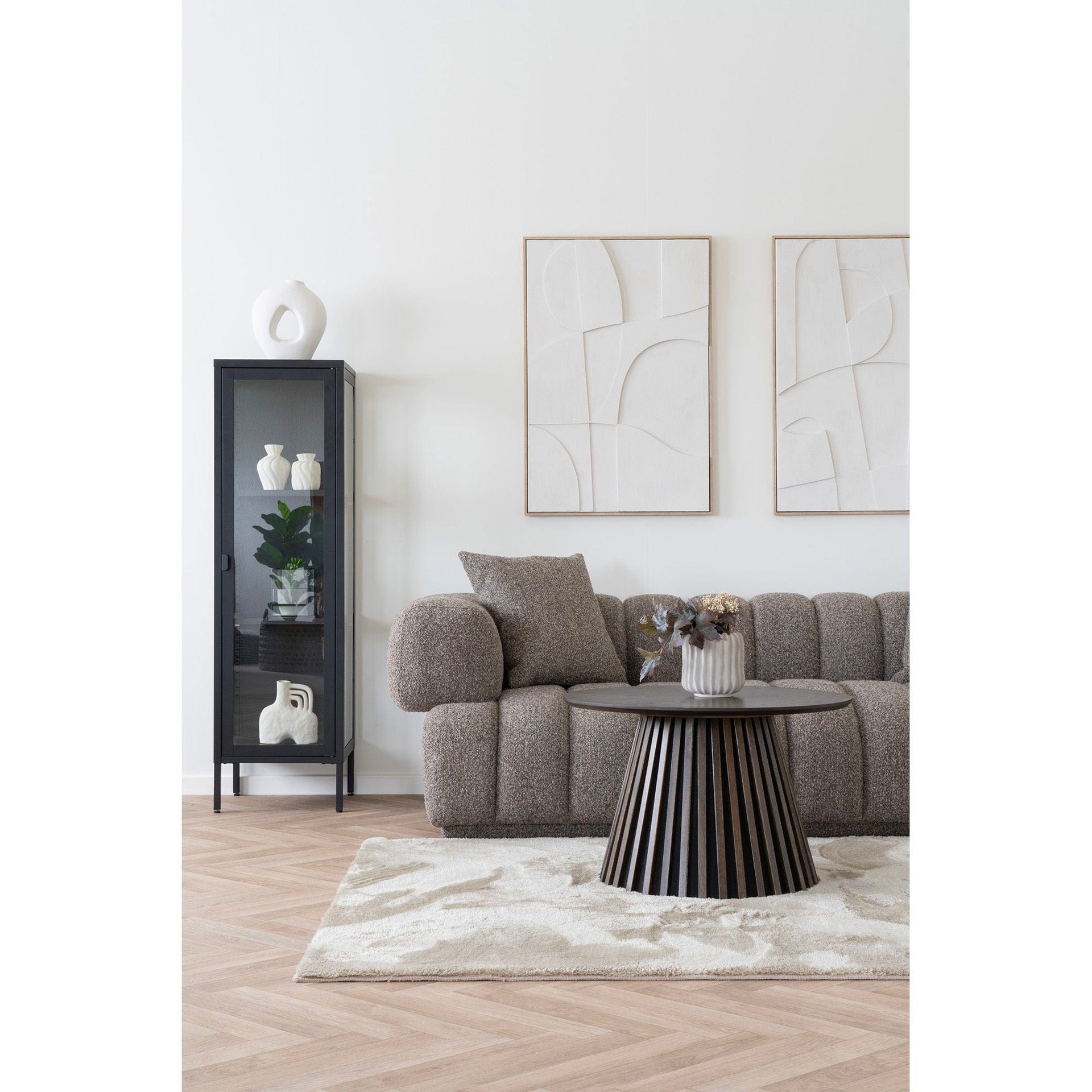 Modern living room with gray sofa, black side table, and abstract art on white walls.