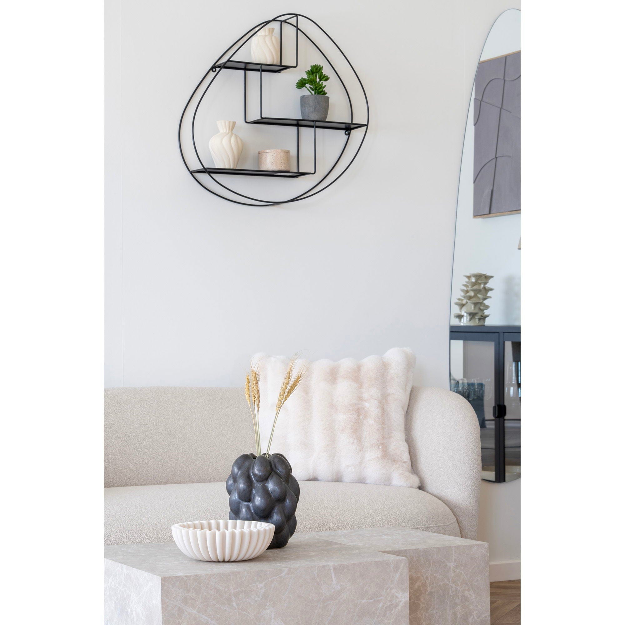 Modern living room with a white sofa, decorative pillows, and a wall shelf.