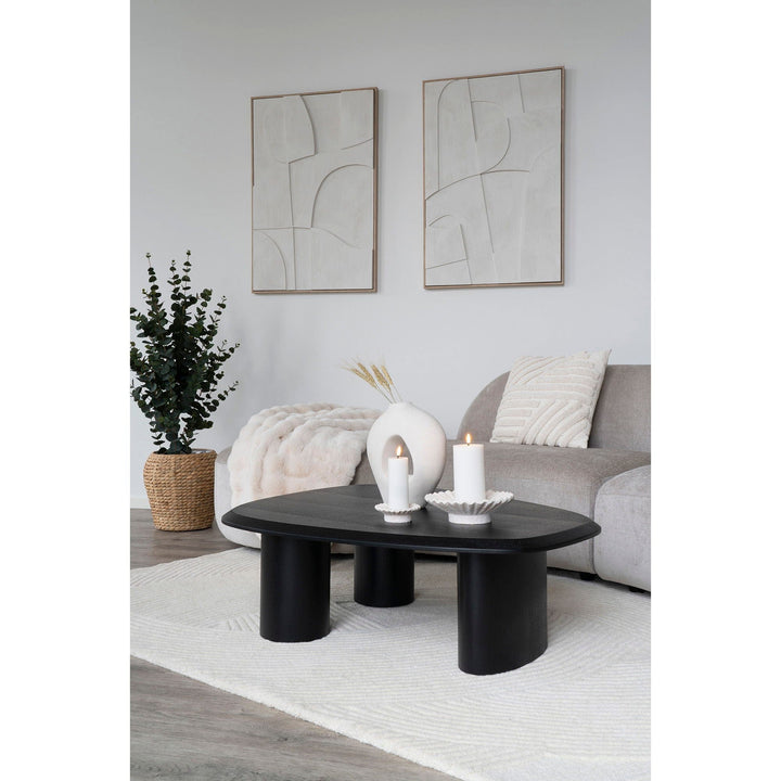 Modern living room with a black coffee table, gray sofa, and abstract art.