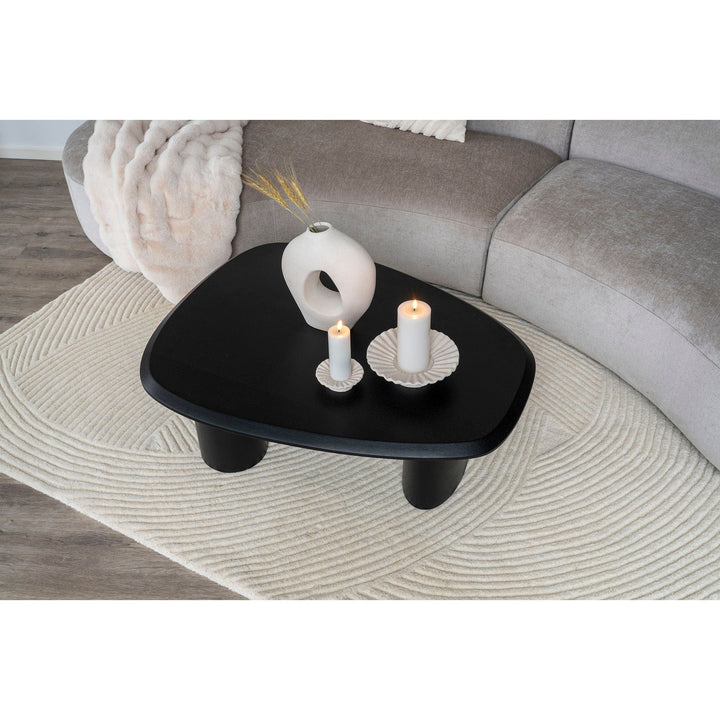 Black coffee table with decorative items in a living room.