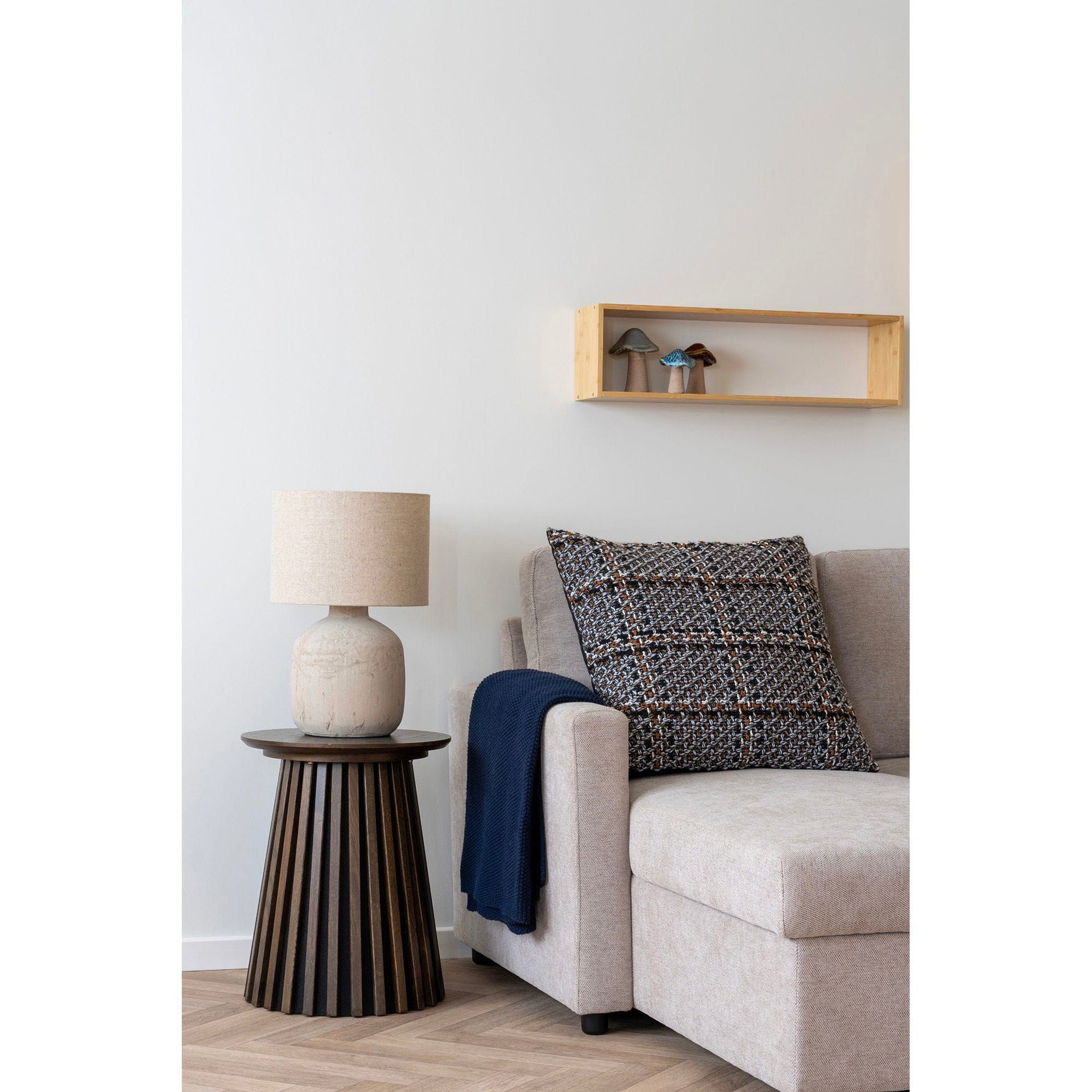 Cozy corner of a living room with a sofa, pillow, and lamp.