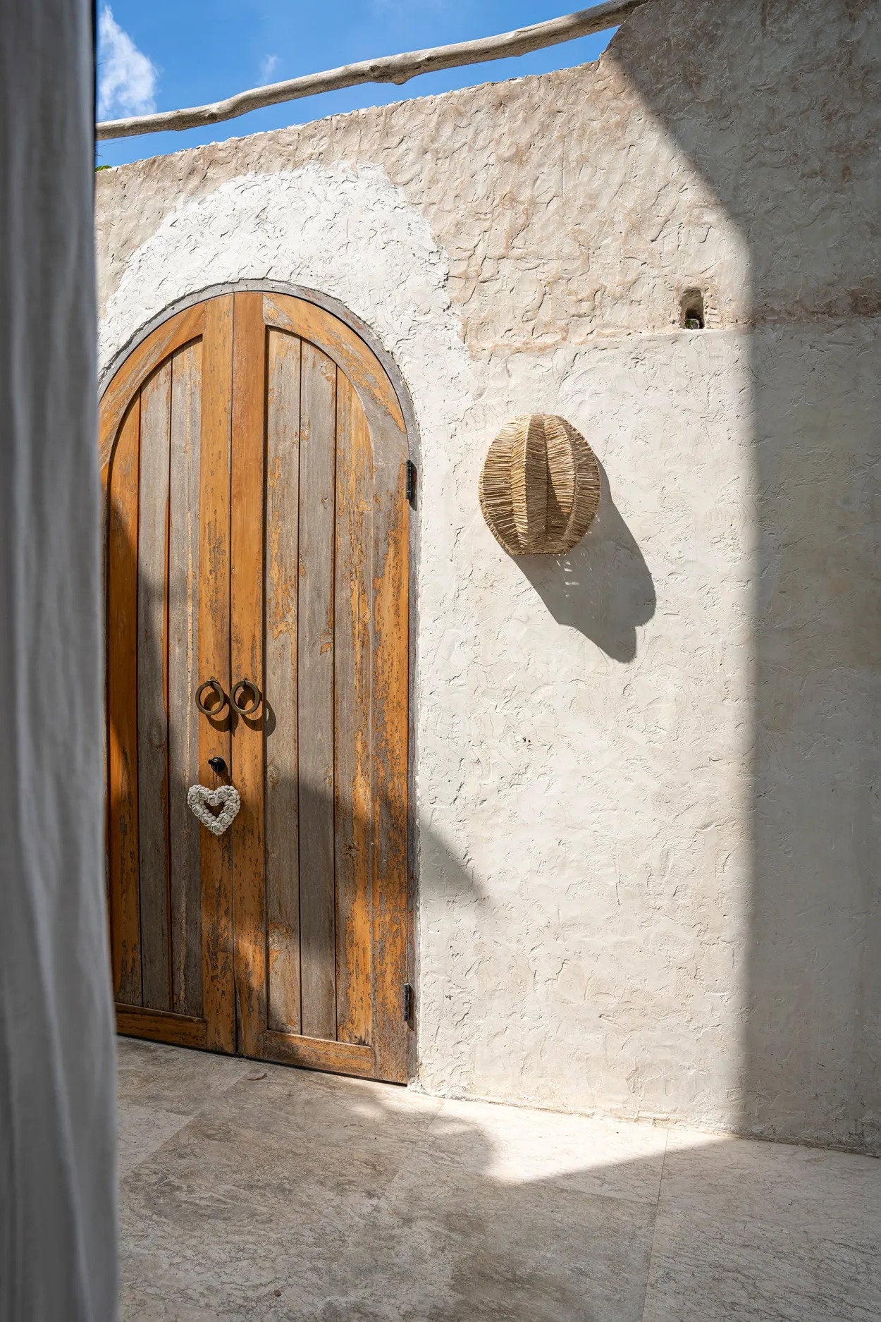 Wooden door on a stone wall with a blue sky background