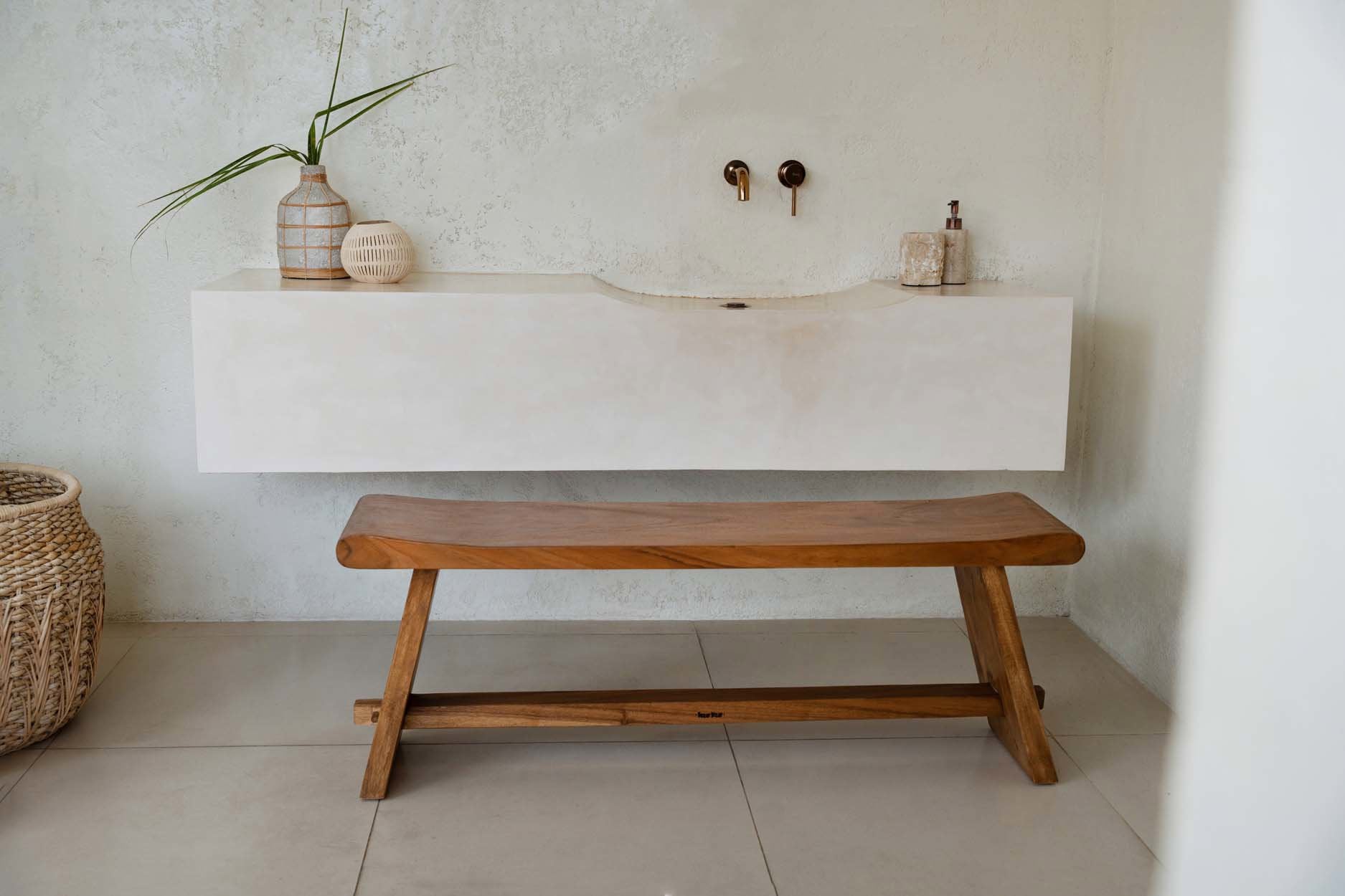 Bathroom with a wooden bench in front of a white sink.