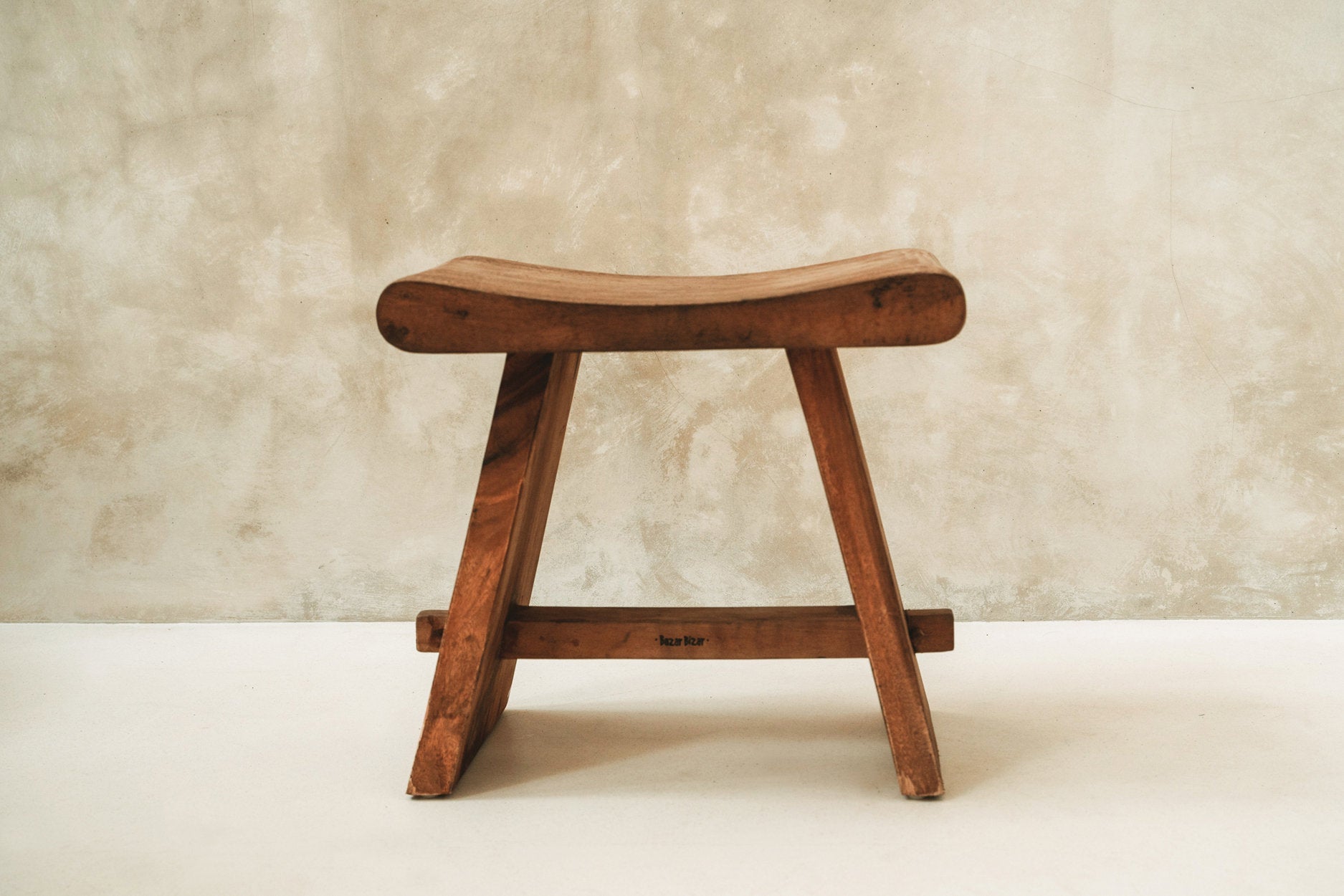 Wooden stool against a textured beige wall