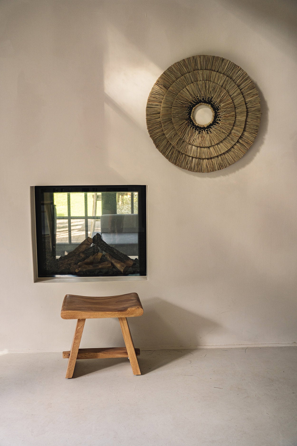 Wooden stool in front of a wall with a framed picture and a decorative circular wall art.