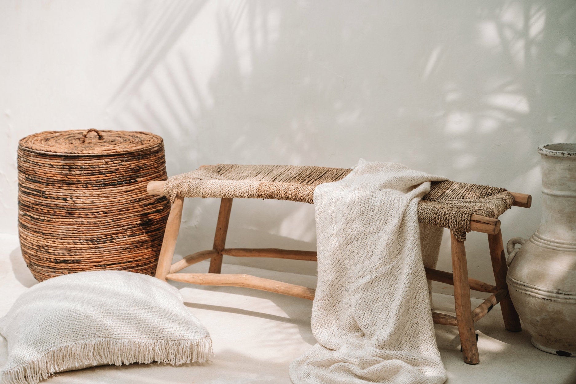 Woven basket, wooden stool, and textured rug against a white wall
