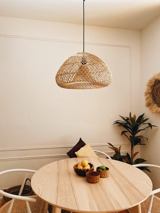 "Dilor Rattan Lampshade, 50cm, handcrafted, hanging above a small dining table, creating a serene boho ambiance."