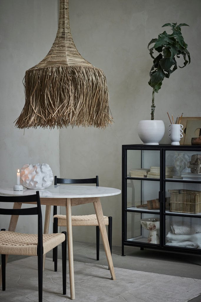Sannia Vase White 29X29X20 cm displayed on a shelf in a modern dining room setting with natural decor elements.