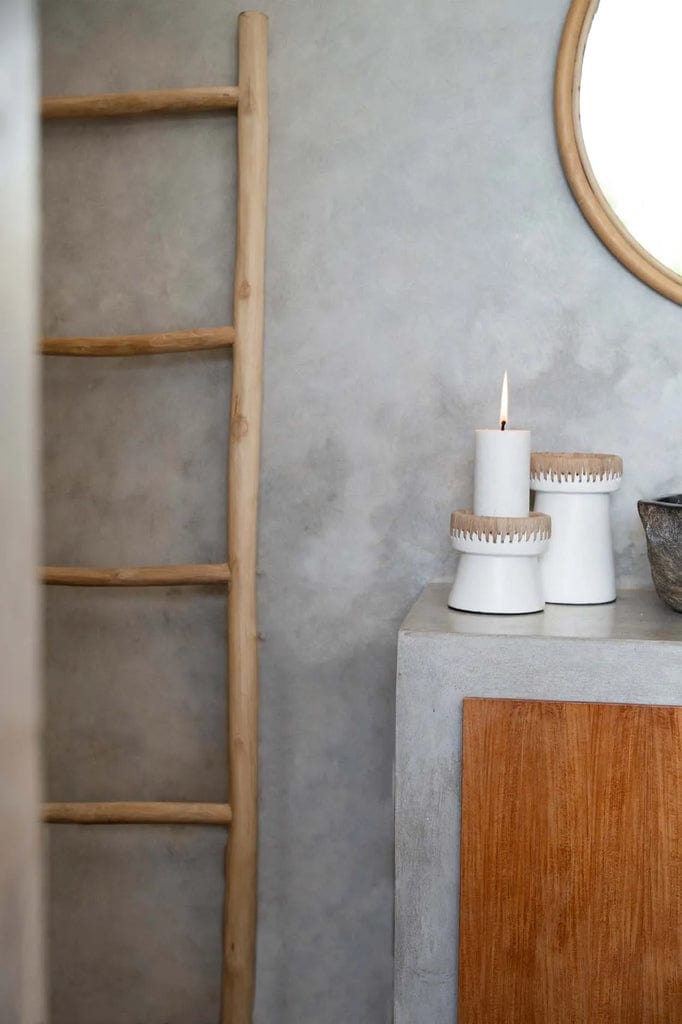 Pretty white natural terracotta and raffia candle holder on a concrete surface.