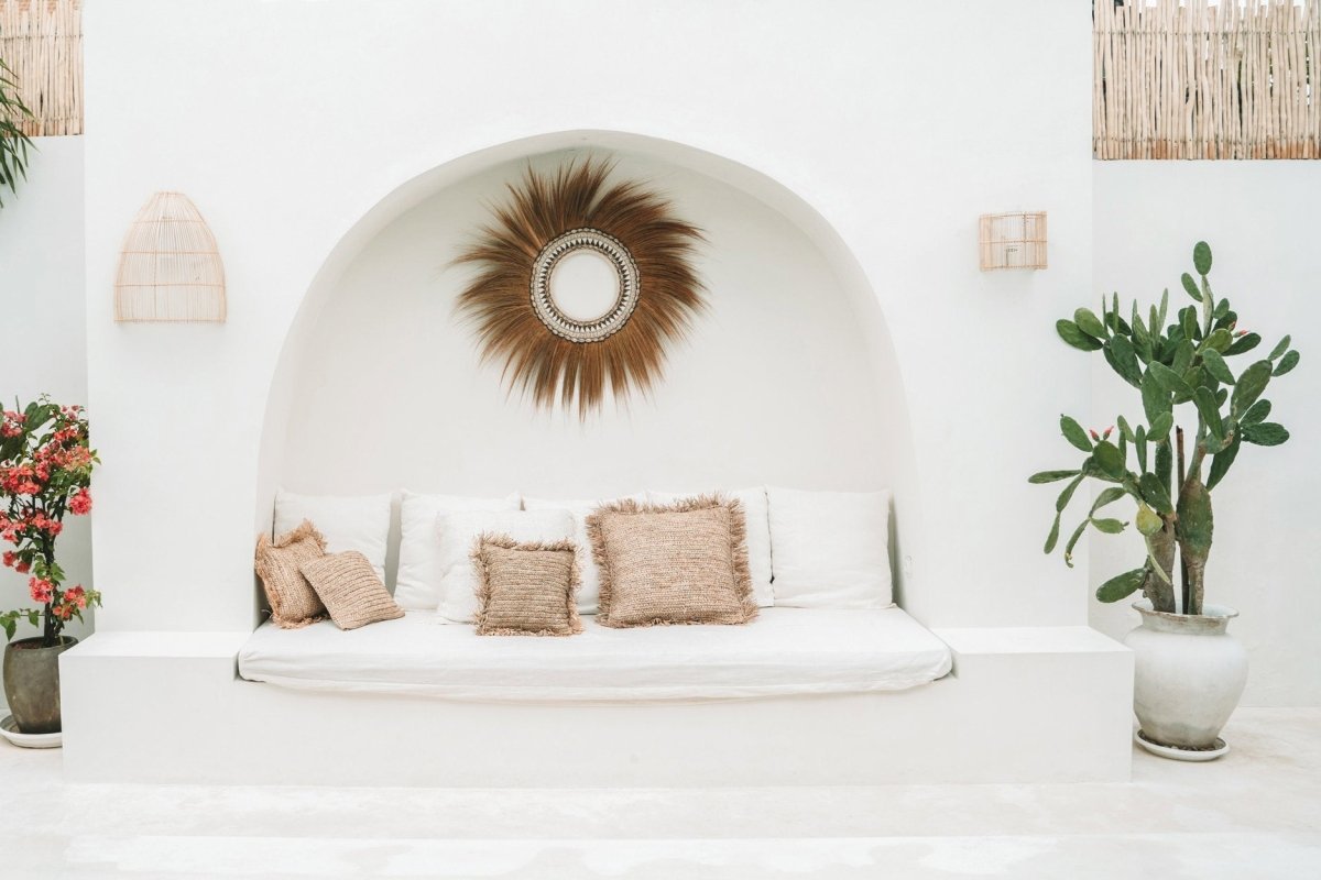 Cushions on white outdoor sofa with green plant and mirror