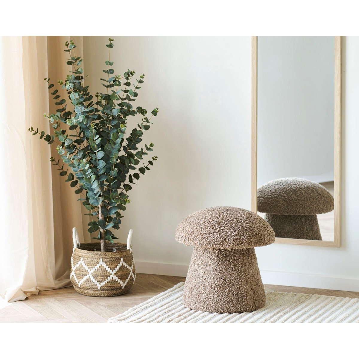 Decorative mushroom-shaped stool next to a potted plant in a room with a mirror on the wall.