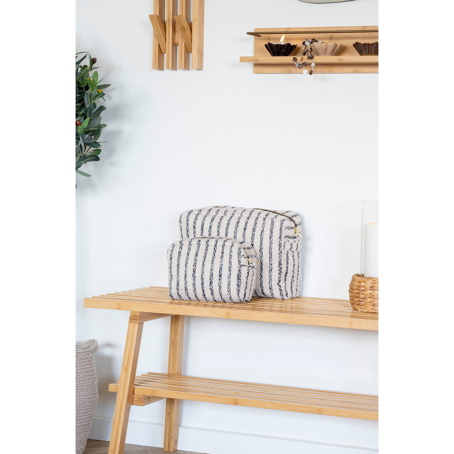 Striped fabric bags on a wooden shelf against a white wall.