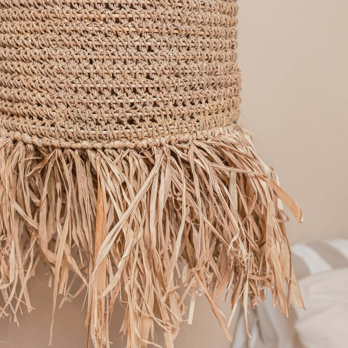Close-up of a woven basket with fringes on a neutral background