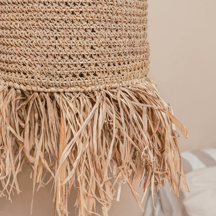 Close-up of a woven basket with fringes on a neutral background