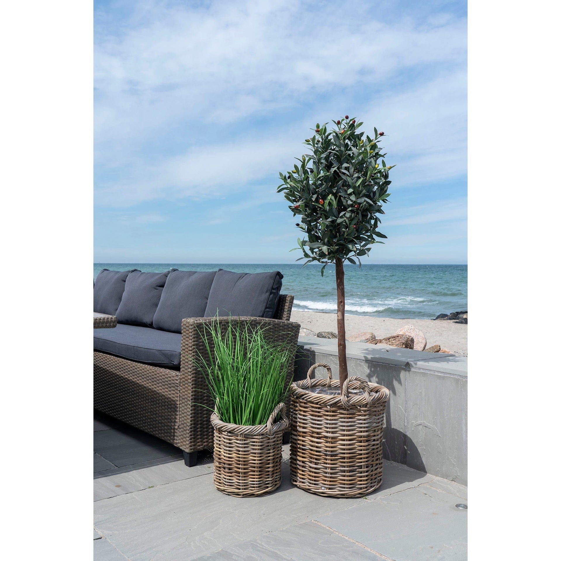 Outdoor patio with wicker planters and a sofa by the beach