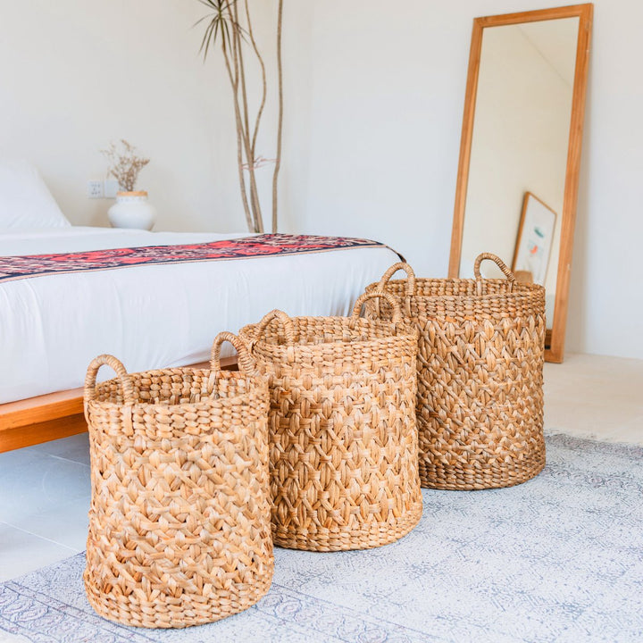 Three woven baskets on a bed in a bedroom setting