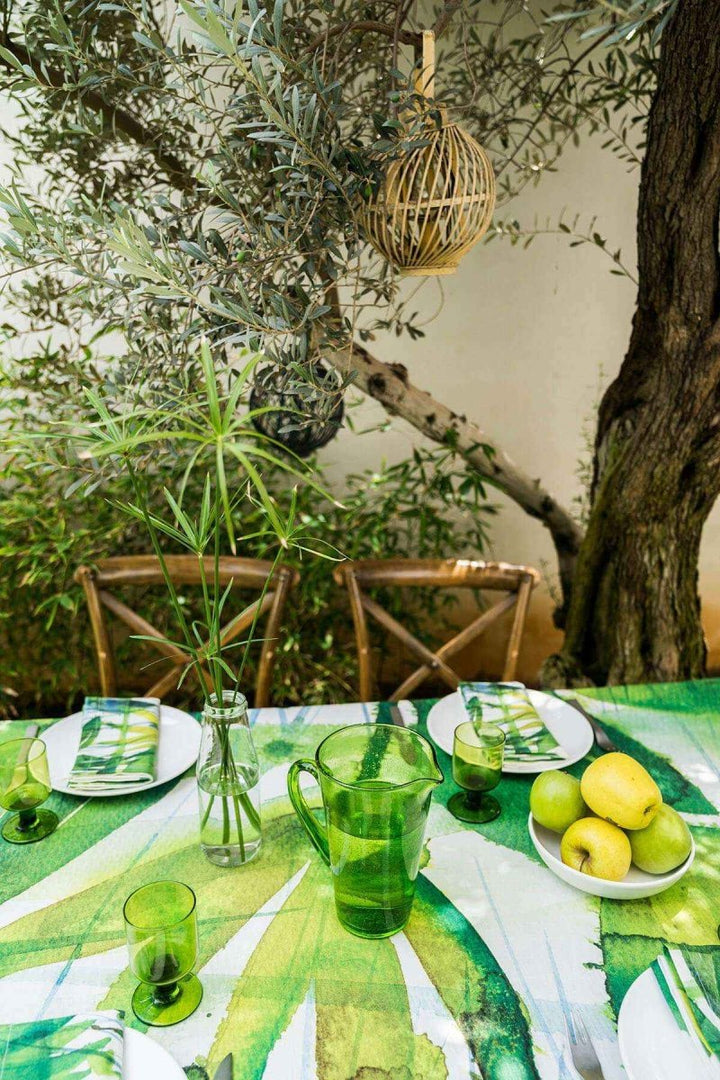 Outdoor setting with a table set for a meal, green tablecloth, and natural elements.