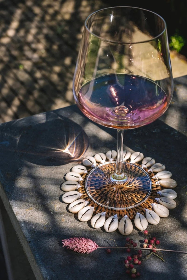 Wine glass with pink wine on a stone surface with decorative shells