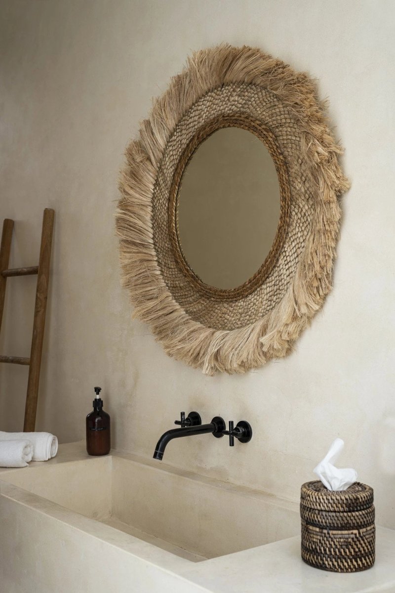 Bathroom with a textured round mirror, sink, and decorative elements.