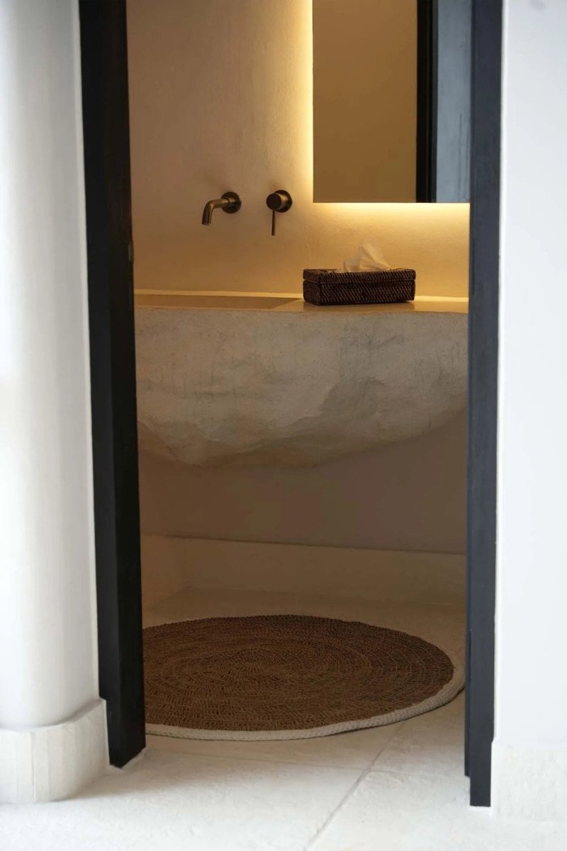 Bathroom interior with a sink and mirror, featuring a textured rug on the floor.