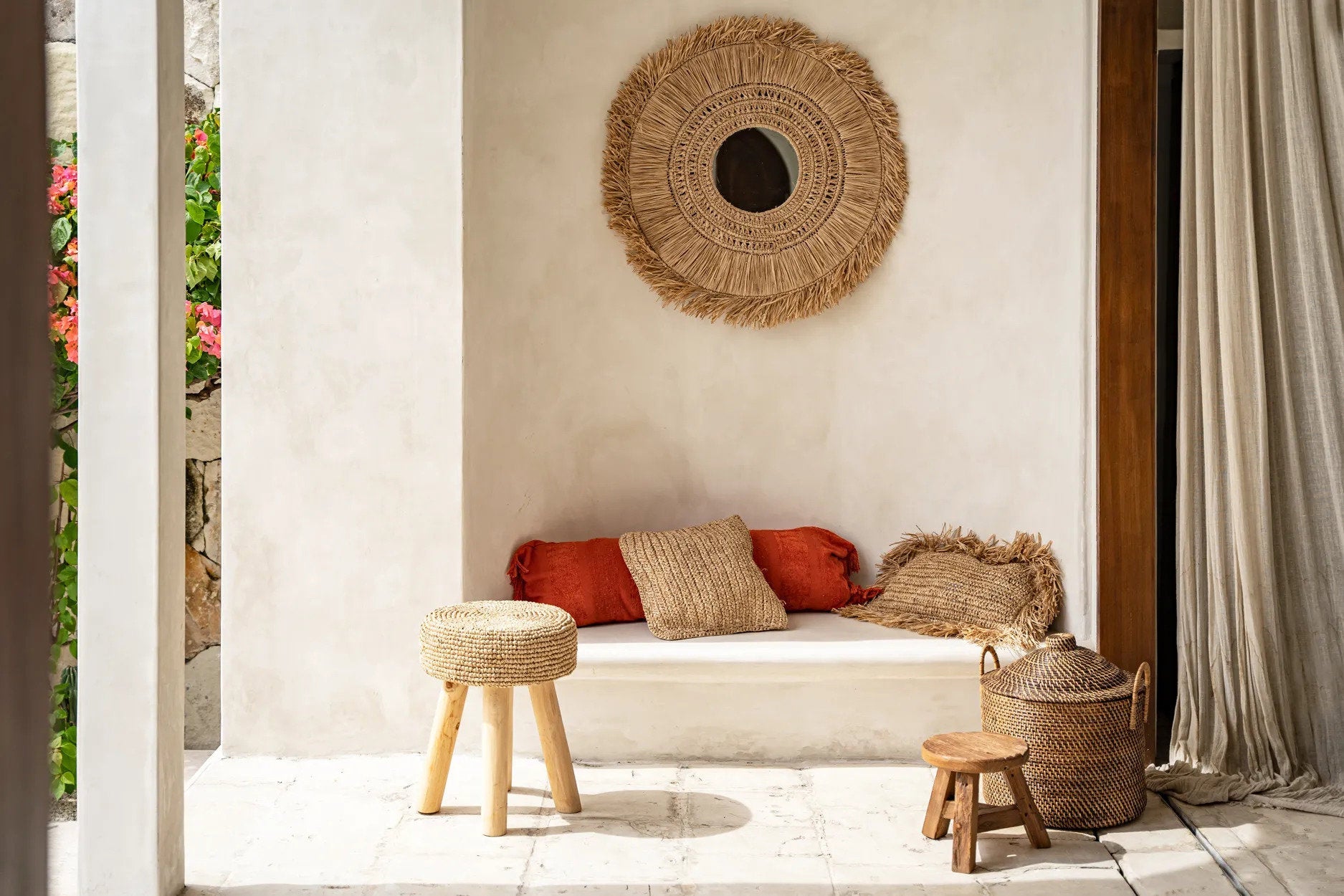 Cozy outdoor seating area with a beige sofa, red cushions, and woven decor items.
