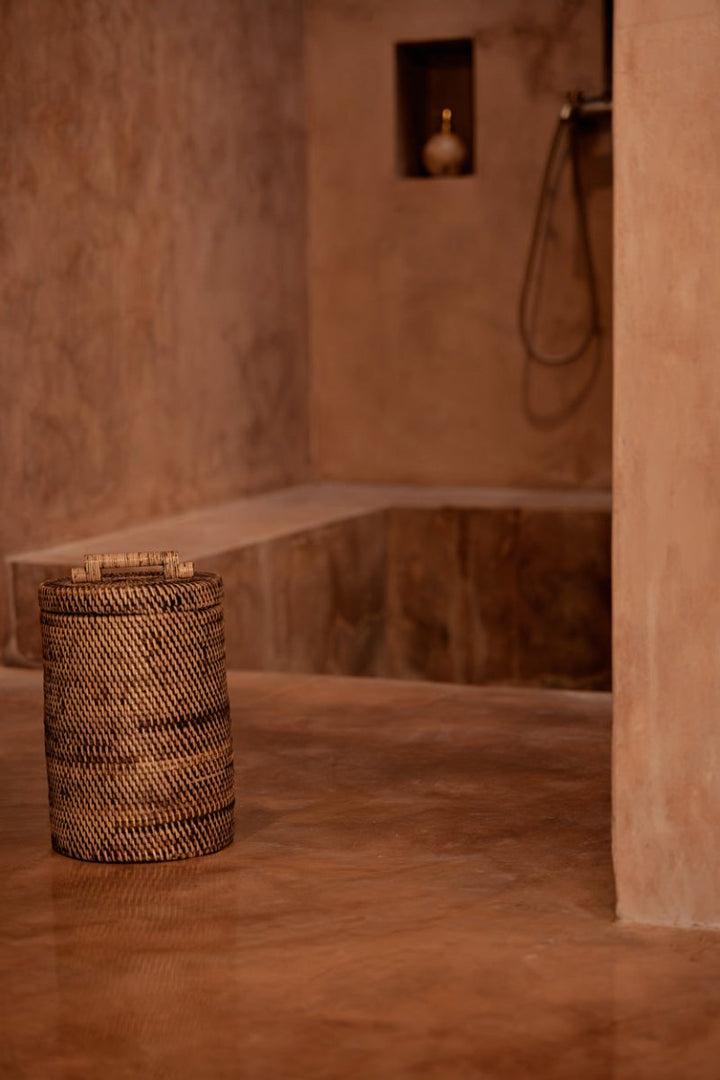 Wicker basket in a rustic bathroom setting with stone walls and a shower head.