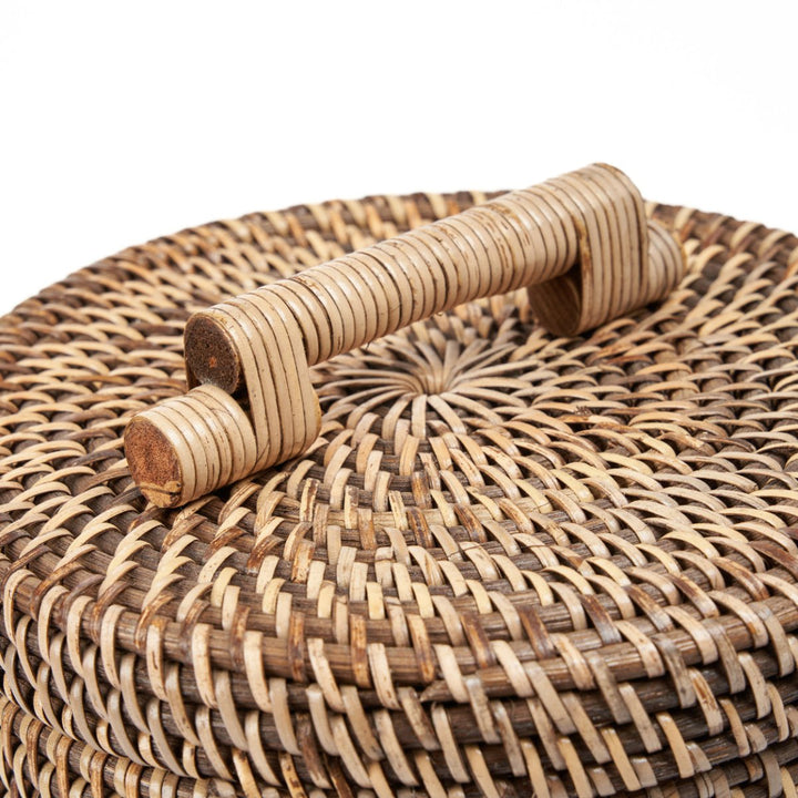 Close-up of a woven rattan box with wooden handles on a white background