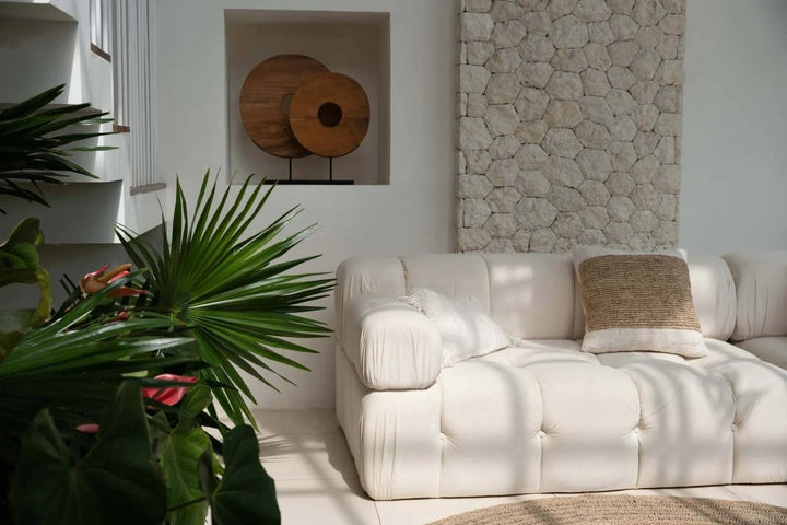 White sofa in a living room with plants and stone wall decor