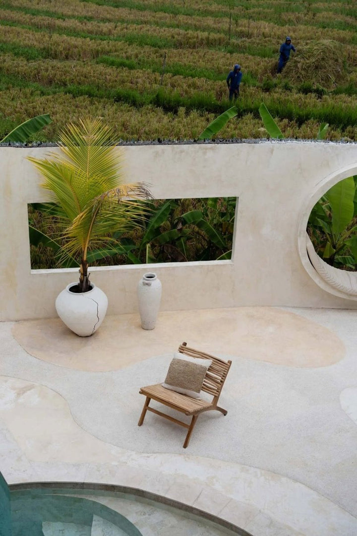 Modern outdoor setting with a bench, potted plant, and vases in a scenic background.