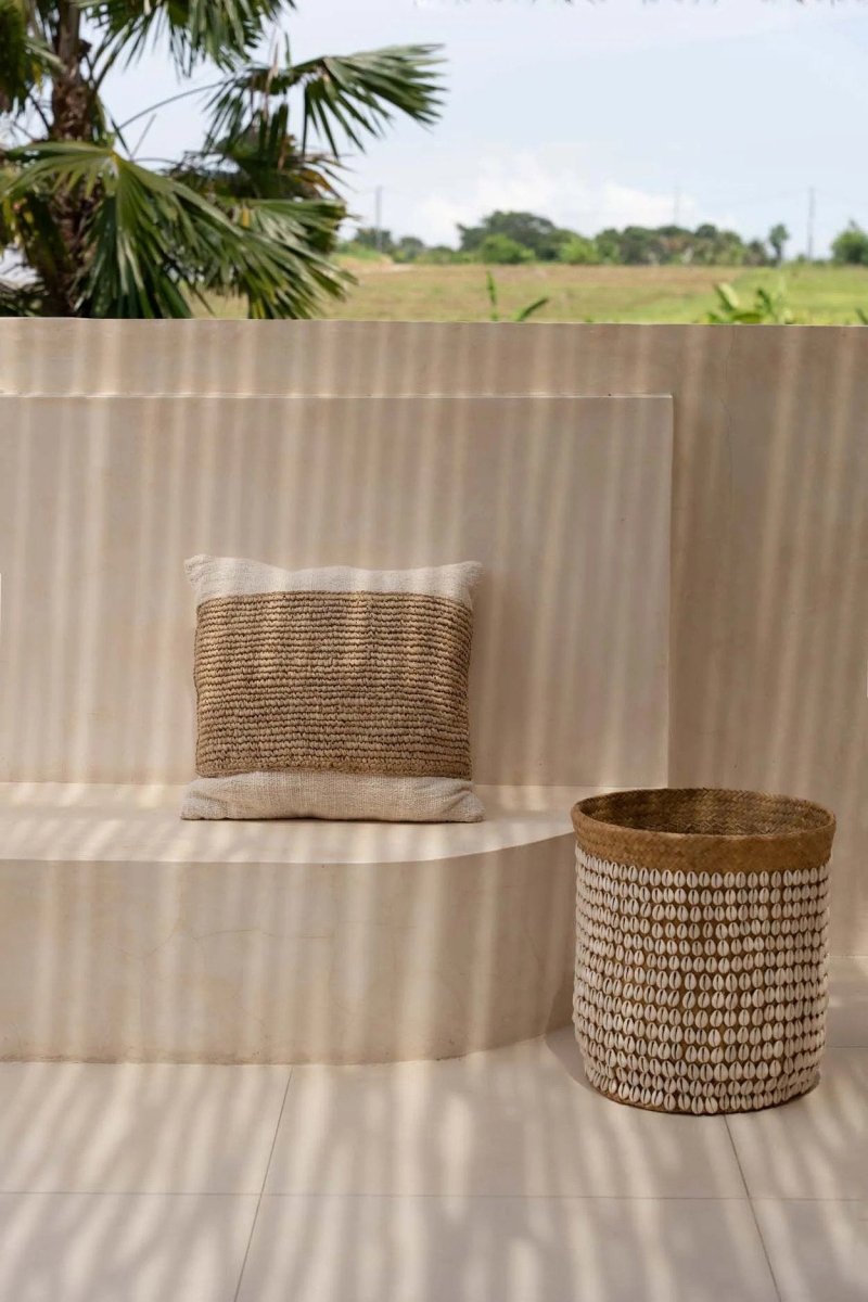 Woven basket and pillow on a striped surface with a natural outdoor setting