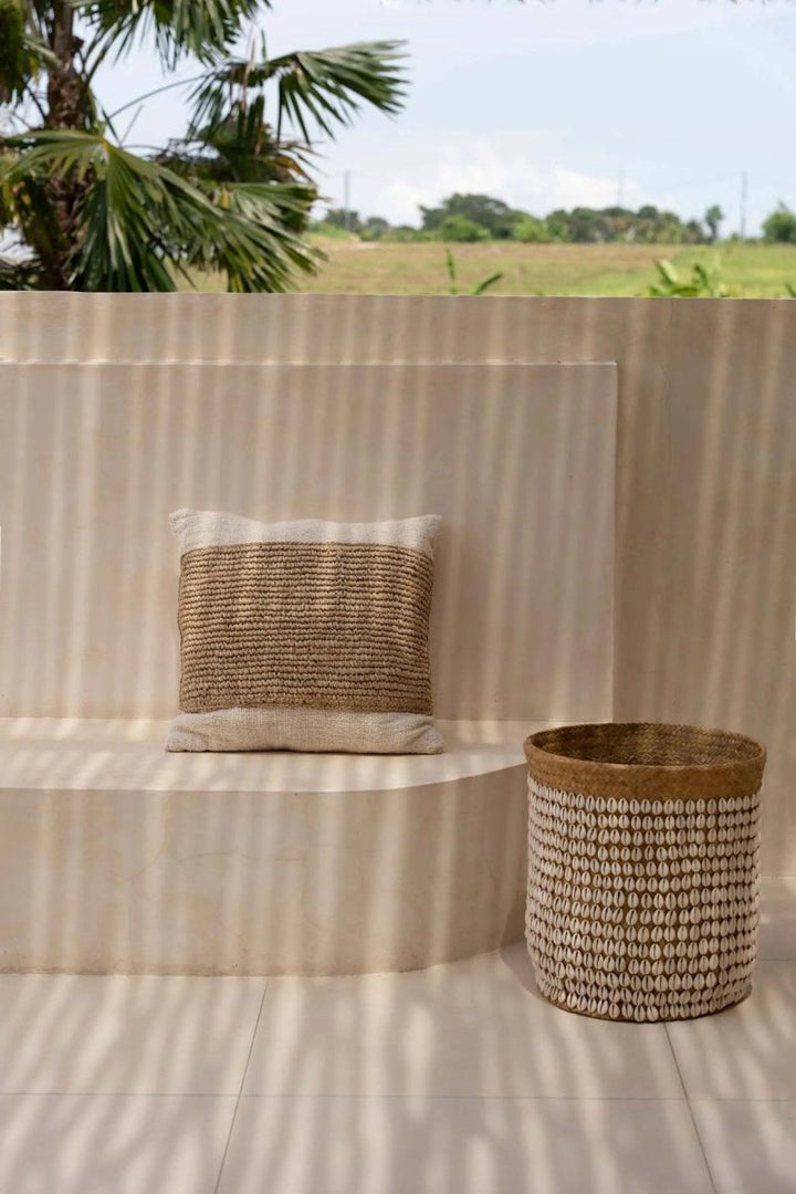 Woven basket and pillow on a striped surface with a natural outdoor setting