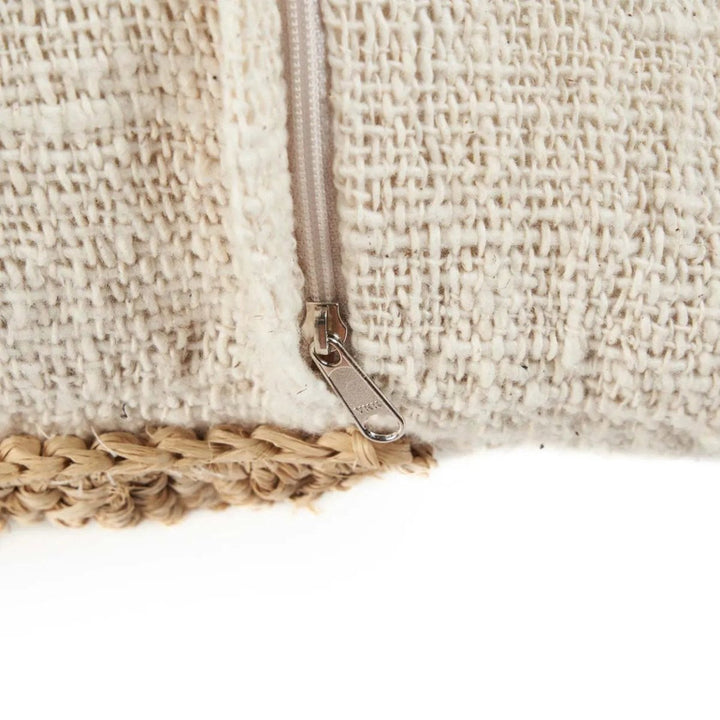 Close-up of a textured beige bag with a zipper and woven handle on a white background
