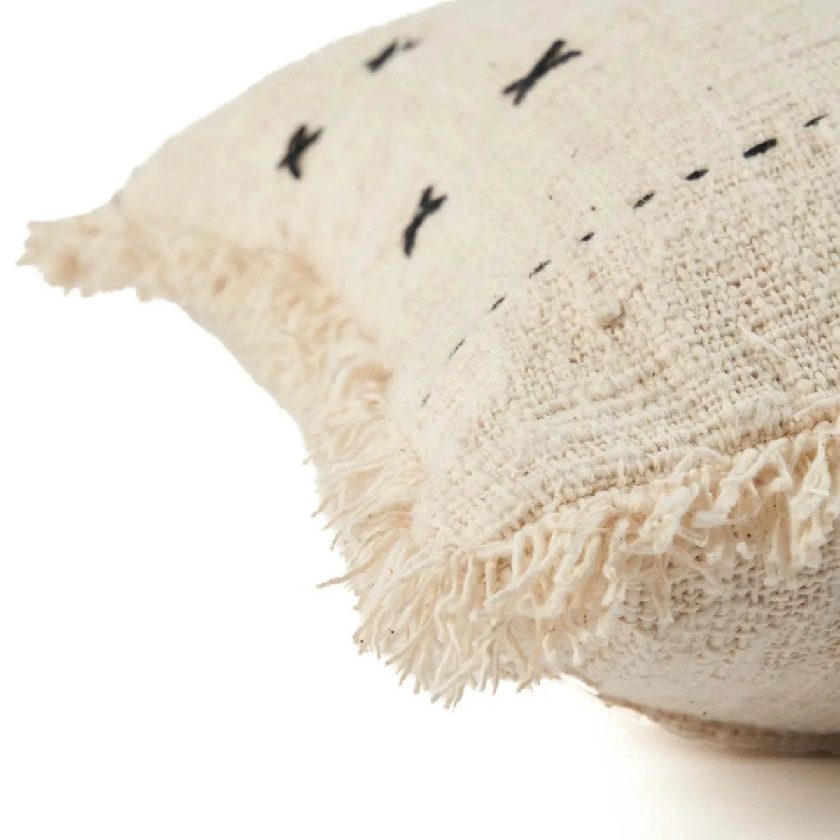 Textured beige pillow with black embroidered patterns on a white background