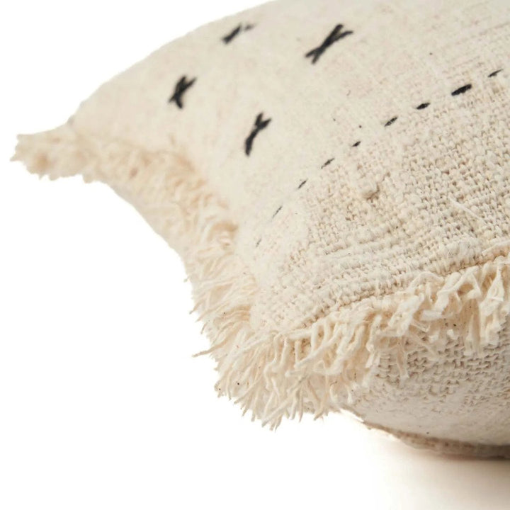 Textured beige pillow with black embroidered patterns on a white background