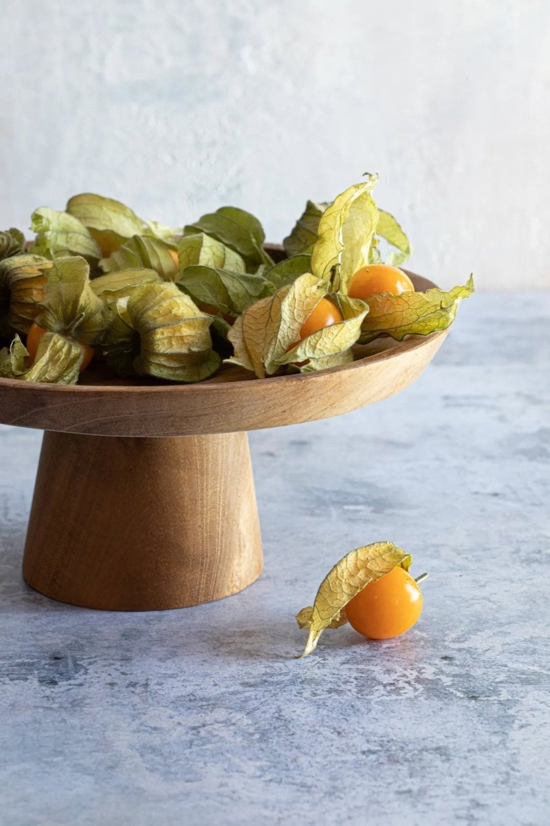 Wooden cake stand withPhysalis on a light gray background