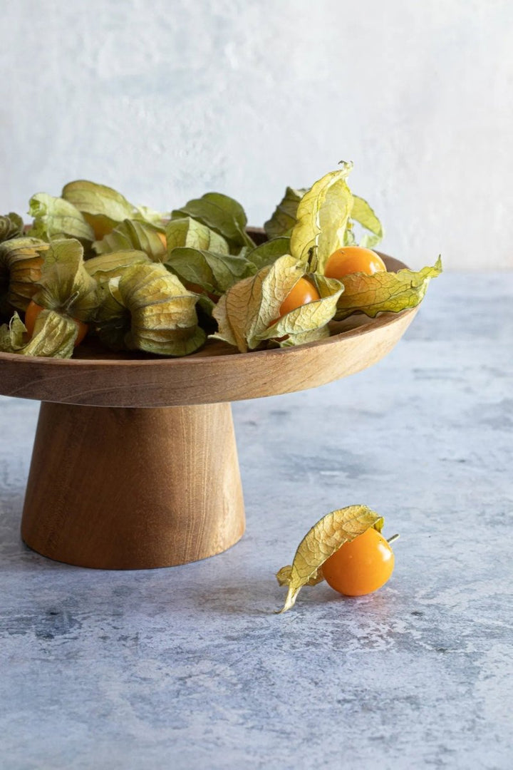 Wooden cake stand withPhysalis on a light gray background