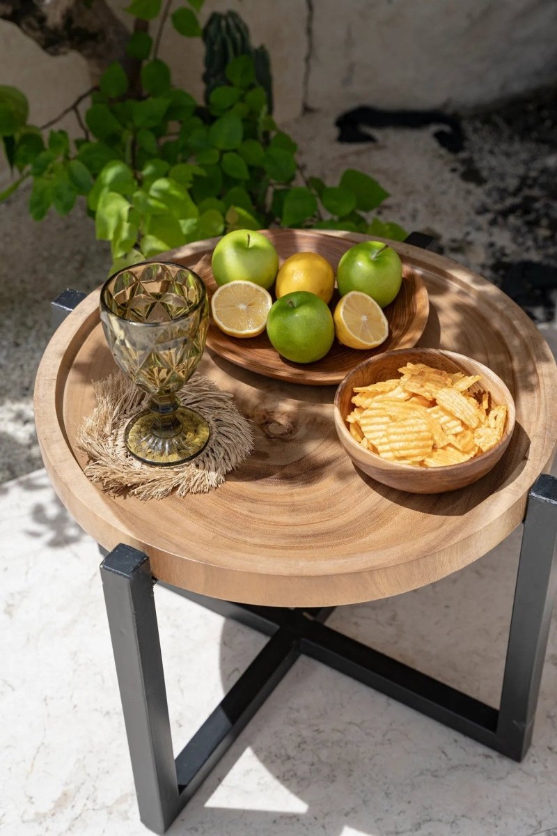 Small wooden table with snacks and drinks on a stone surface