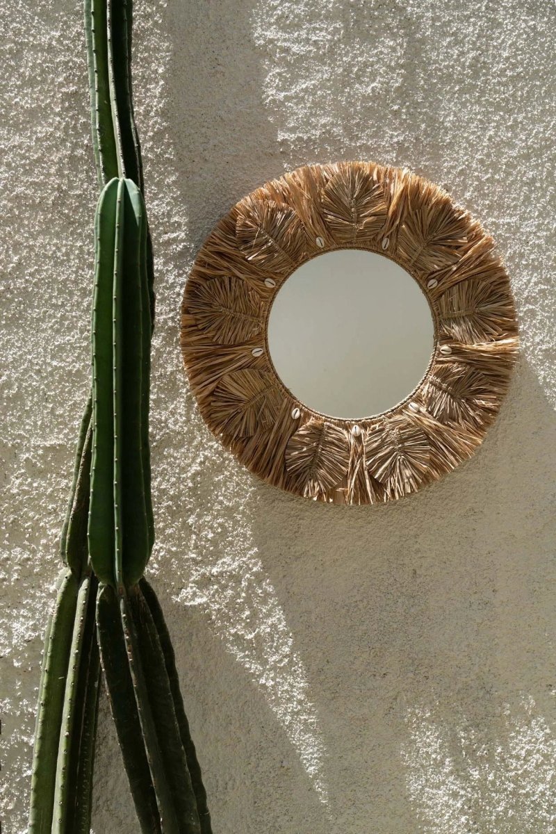Round  mirror with leaf-like design on a textured wall