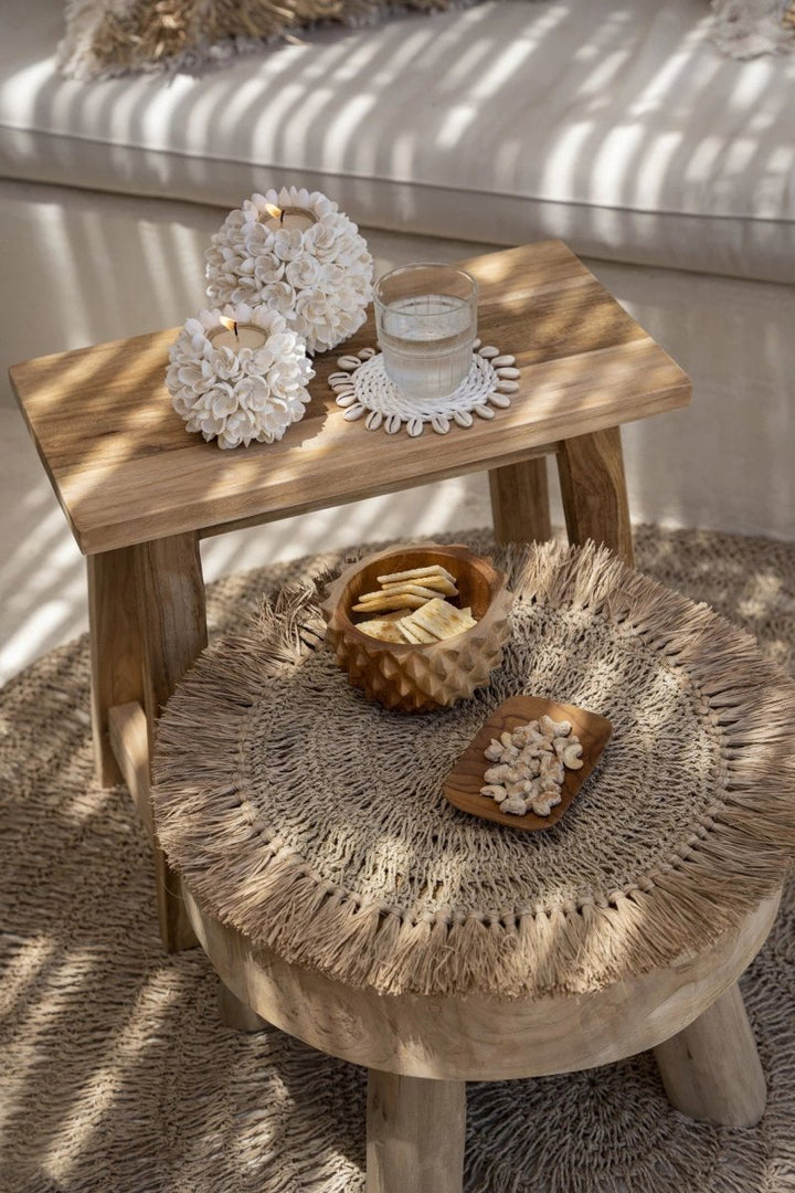 Small wooden table with decorative items on a textured rug