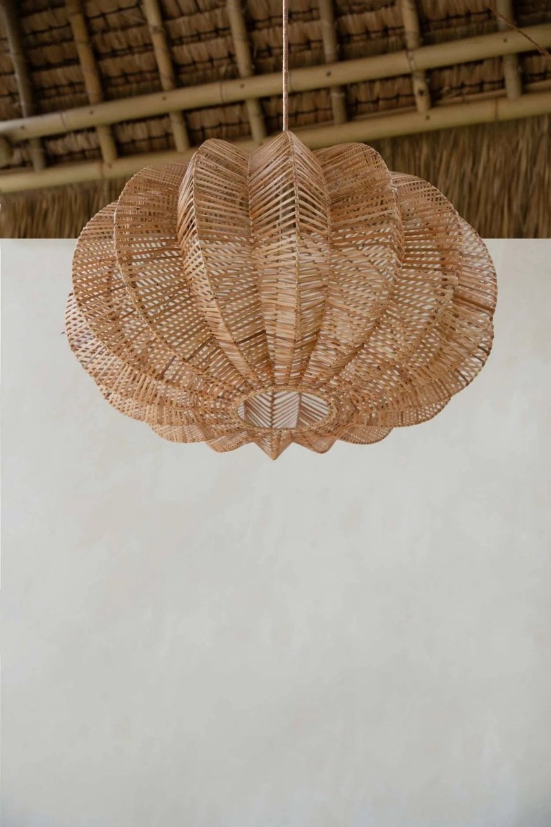 Woven rattan ceiling light fixture on a white surface with a wooden background