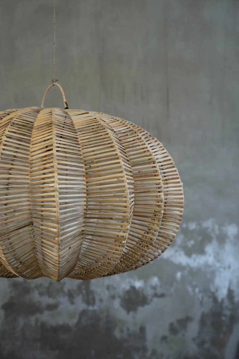 Woven rattan pendant light against a textured gray wall
