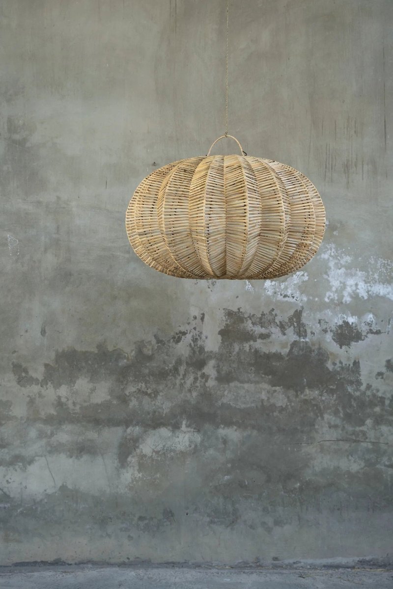 Woven rattan pendant light hanging against a textured gray wall.