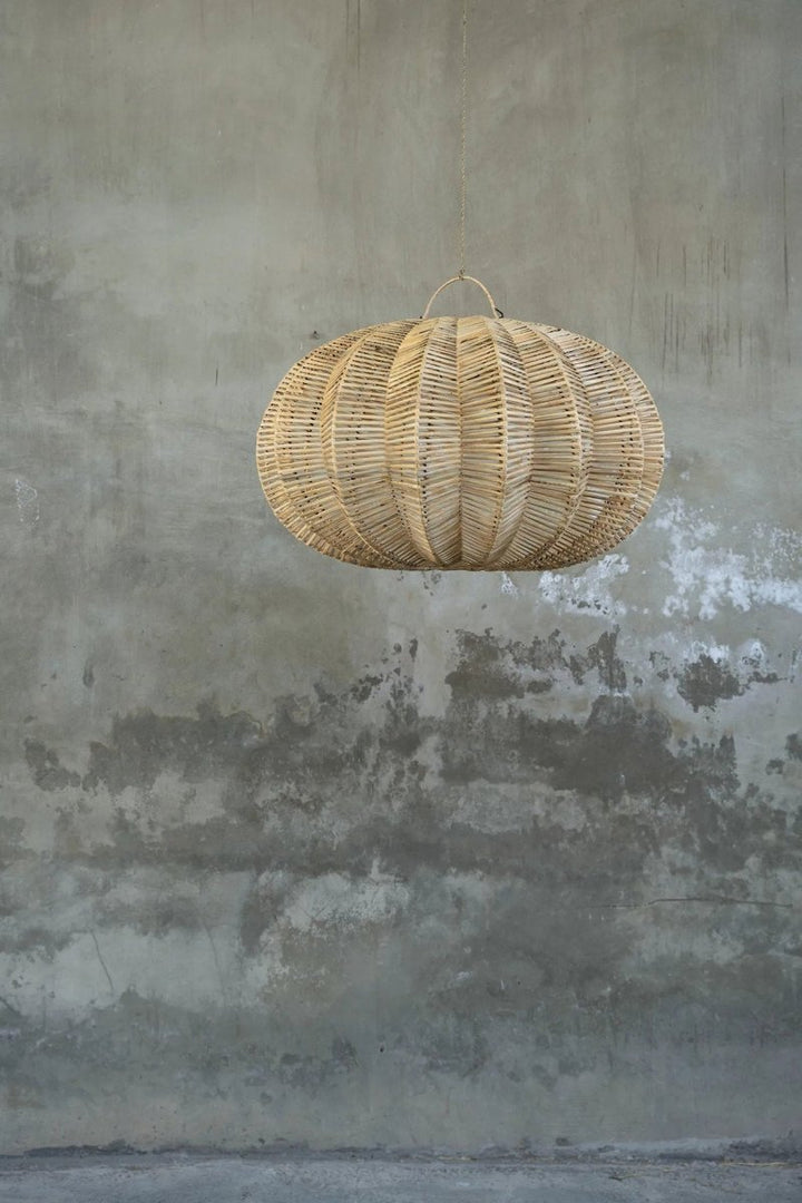 Woven rattan pendant light hanging against a textured gray wall.