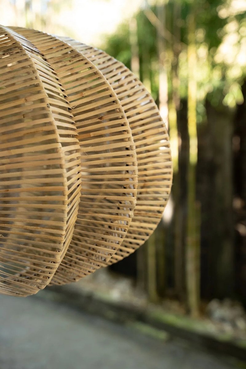 Close-up of a woven rattan lampshade with blurred natural background