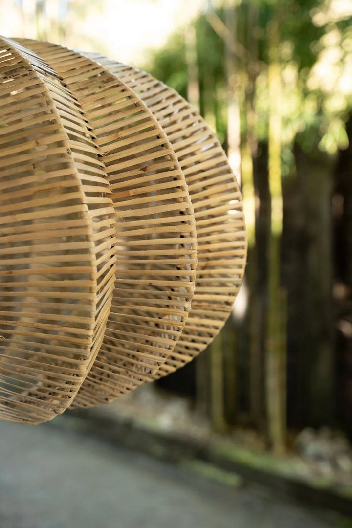 Close-up of a woven rattan lampshade with blurred natural background
