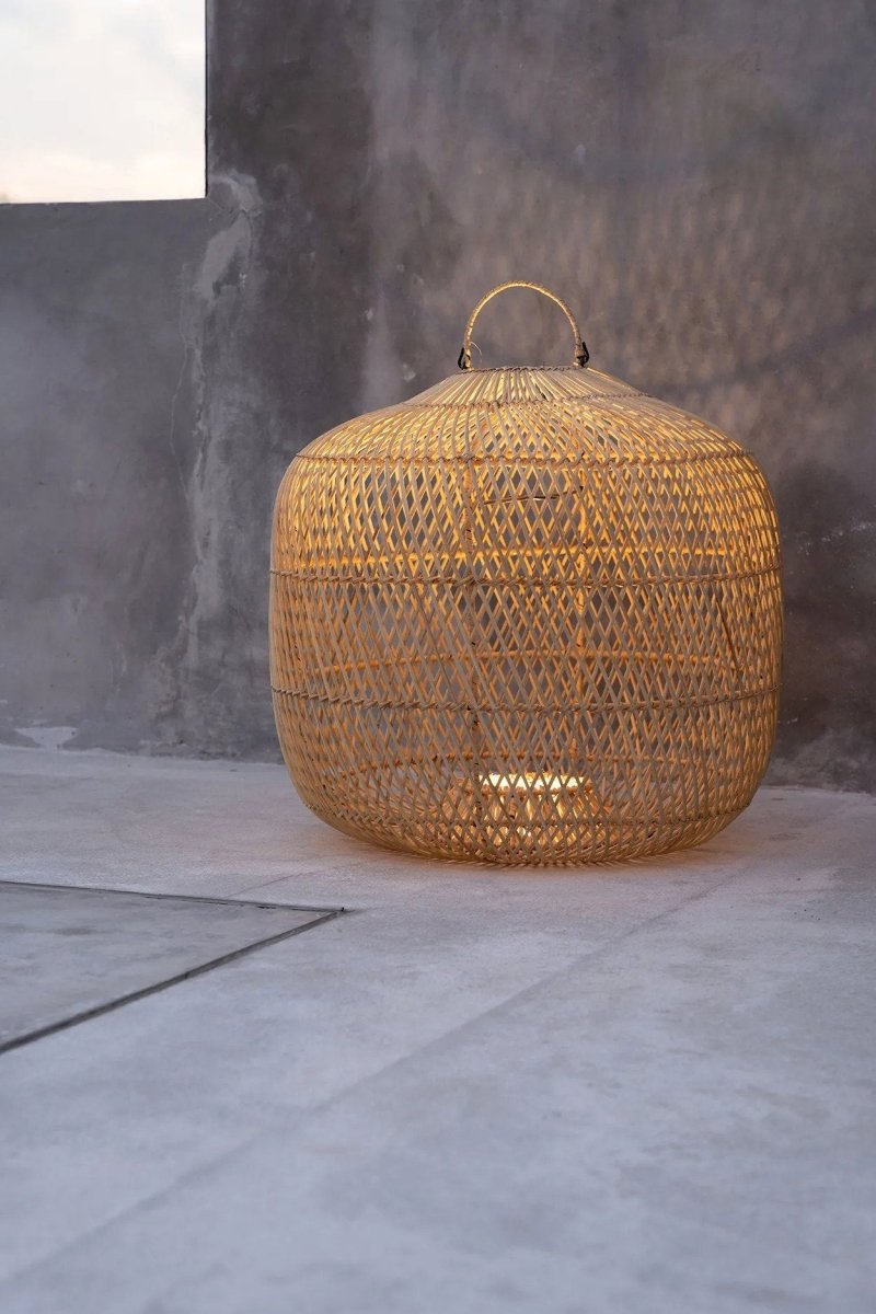 Woven rattan lamp with a handle on a gray surface and background