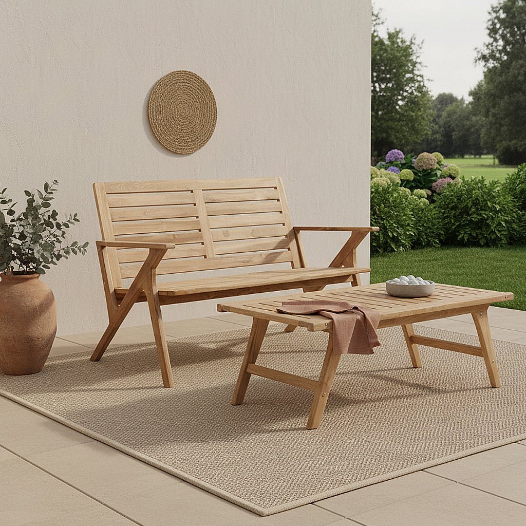Wooden outdoor bench and table set on a patio with plants and flowers in the background.