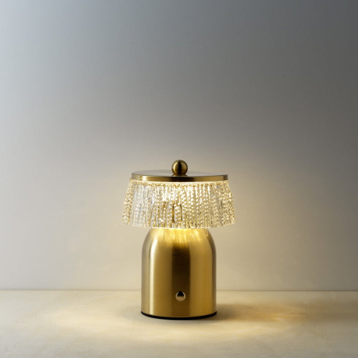 Gold table lamp with decorative crystal shade on a neutral background